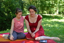 friends praying for each other sitting outdoors on a blanket in a park