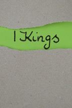 torn open kraft paper over green paper with the name of the book 1 Kings