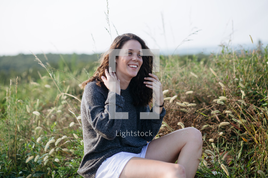 woman sitting in a field of tall grasses