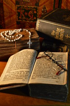 a rosary and reading glasses on an old Bible 