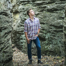 A young man standing in a rocky crevasse.