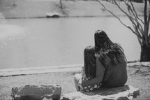 mother and daughter sitting together on a park bench looking out at a lake