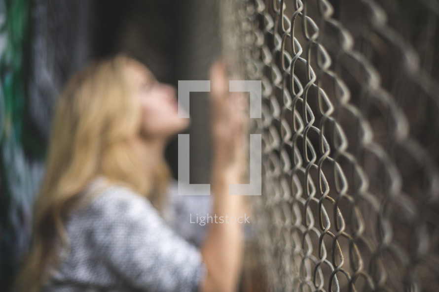 a woman clinging to a chain link fence 