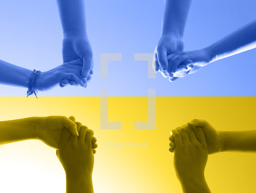 Group of People Praying in a Circle Holding Hands as their Hands Make the Shape of the Cross