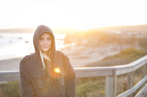 portrait of a woman in a hoodie standing on a shore 
