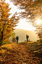 Silhouette of two hikers in autumn mountain forest