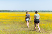 teen girls walking through a field of yellow flowers 