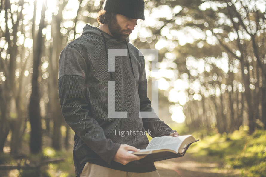 a man reading a Bible alone in a forest 