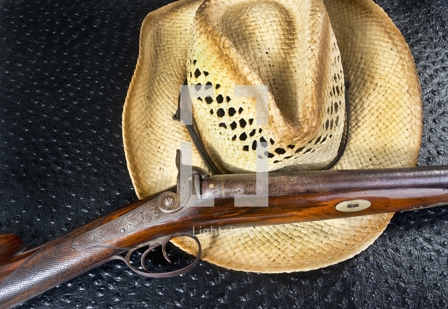 Antique Double Barrel Shot Gun and Straw Hat.