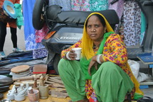 a woman grinding powders and spices in a city market 