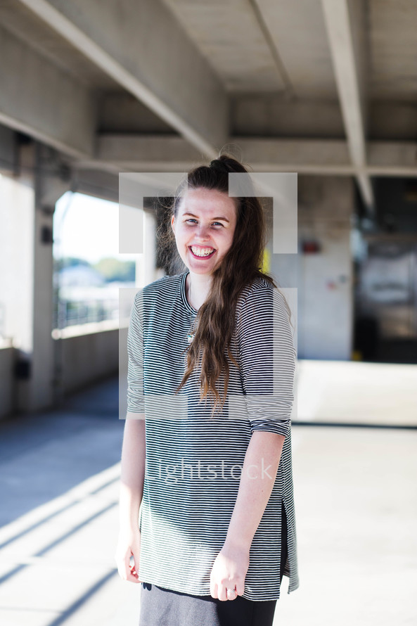 a smiling young woman standing in a parking garage 