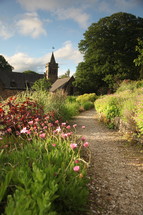 path line with flowers leading to a stone church with steeple 