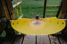 a toddler girl going down a slide 