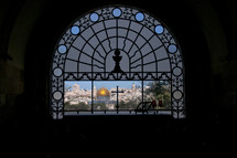 View of the City of Jerusalem through a chruch window with a cross and 2 wine glasses.