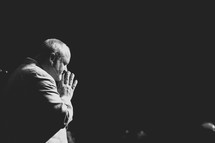 a pastor in prayer during a worship service 