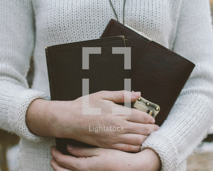 woman holding a Bible and journal close to her heart 
