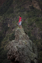 a man standing at the top of a tall rock 