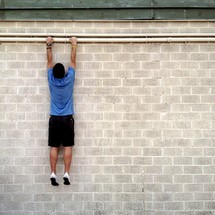 Man hanging on side of a brick wall
