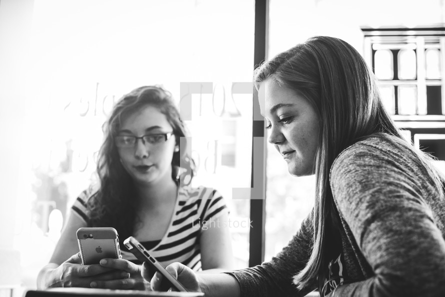 young women at a coffee shop for a Bible study using cellphones 