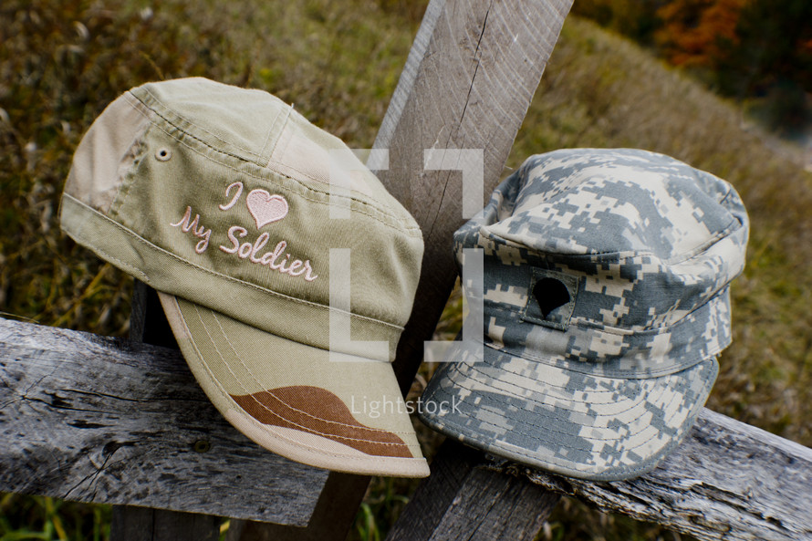 His and hers military hats on a fence post outside.
