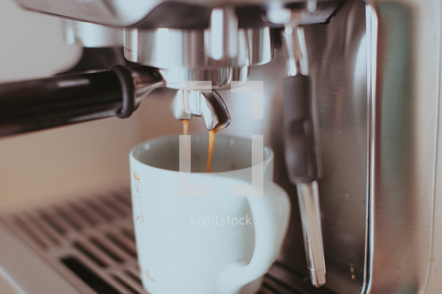 A double espresso shot pouring into a coffee mug.