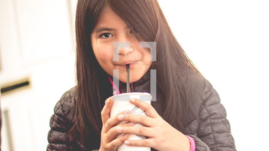 a girl drinking from a straw 