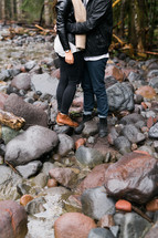 couple hugging standing on rocks 