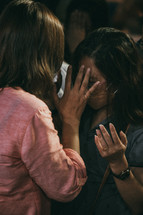 two women comforting each other during a worship service 
