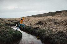 person jumping over a stream 