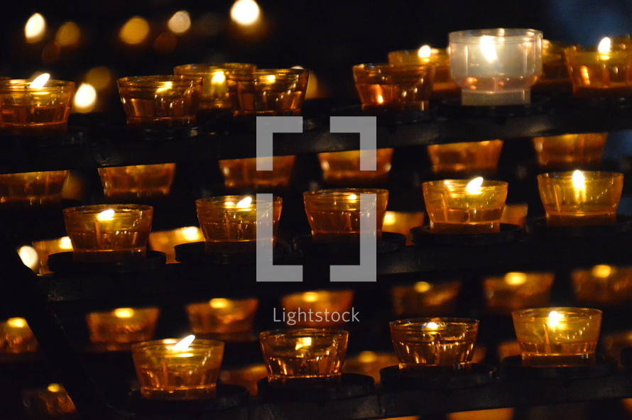 many lit candles in a dark church. 