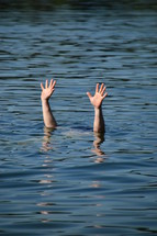 hands raised out of the water for help