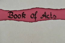 Book of Acts - torn open kraft paper over dark red paper with the name of the book: Acts of the Apostles