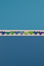 blue, green, and purple hearts in a row on paper 