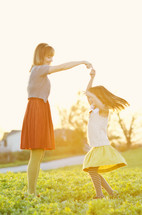 Mother and daughter dancing on a spring day.