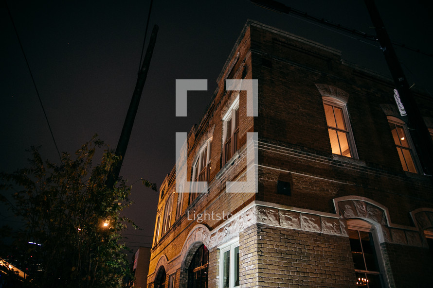 lights on in the windows of a brick building at night 