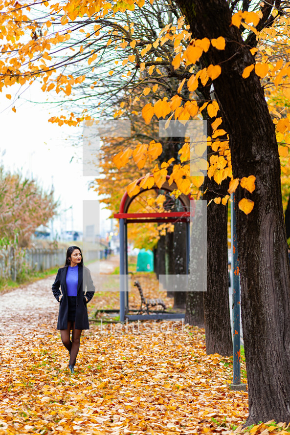 A young woman in a park surrounded by fall colors 