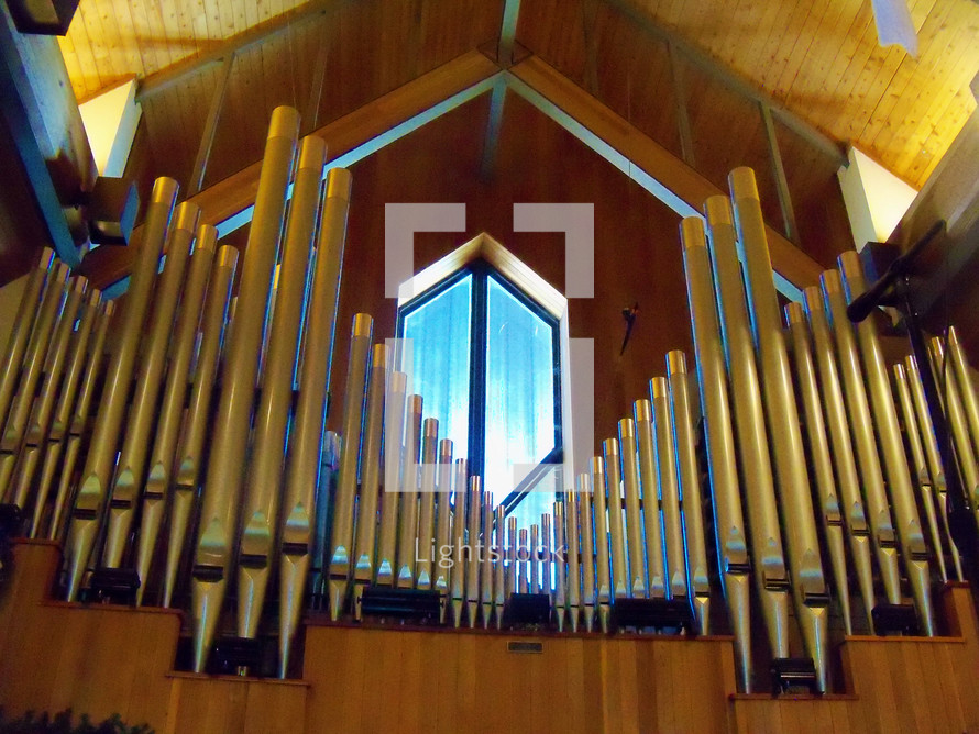 Pipes from a pipe organ in front of a widow