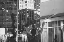 a man with raised hands in a city at night 