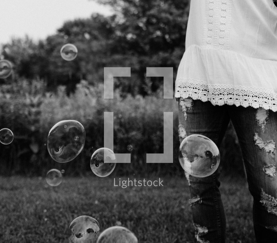 Bubbles floating around a woman standing outside.