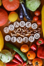 fruits and vegetables with burned wood showing the word thanksgiving.