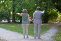 man and woman pointing down different paths