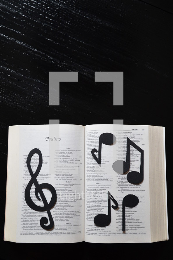 A Bible open to Psalms covered in musical notes.