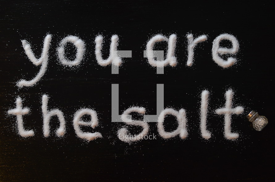 The words, "you are the salt," written with salt on a table.