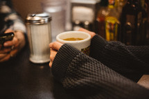 a woman in a sweater holding a mug of coffee 