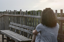 a woman sitting on a boardwalk thinking 