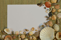 blank paper, and seashells on a beach mat 