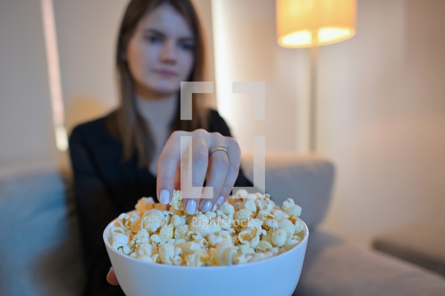 a woman eating a bowl of popcorn 