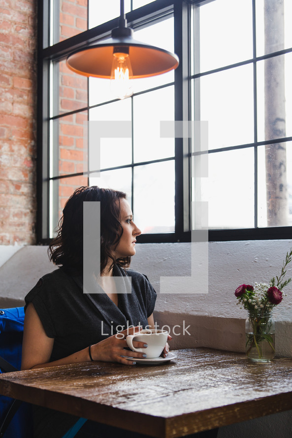 a woman sitting at a window seat in a coffee shop 