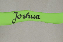 Joshua - torn open kraft paper over green paper with the name of the book Joshua