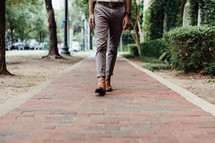 a man walking down a brick sidewalk 